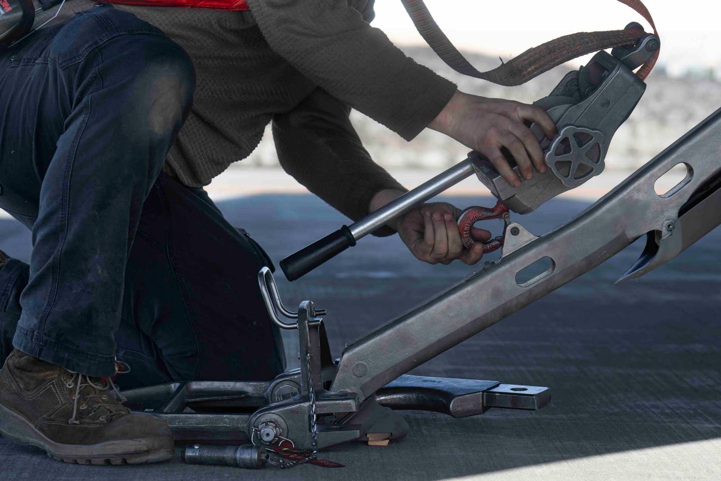 U.S. Air Force Tech. Sgt. Kyle Veurink, an F-22 Raptor craftsman assigned to the 90th Air Maintenance Unit, connects a repositioning tool in preparation for the afterburner run. <em>U.S. Air Force photo by Airman 1st Class J. Michael Peña</em>