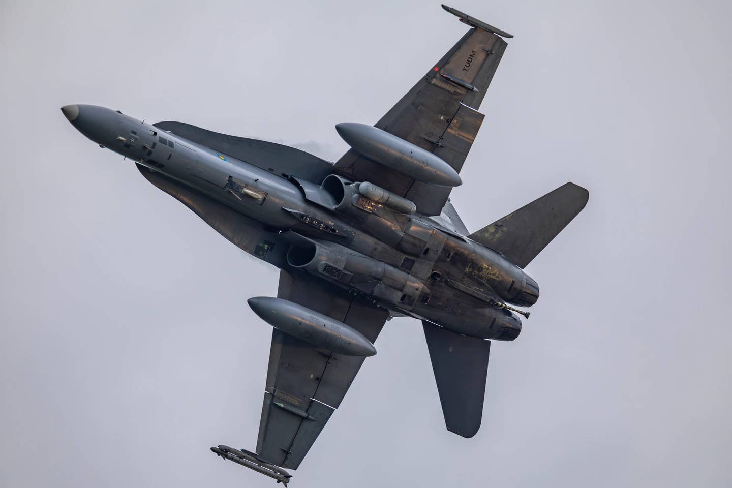 An unedited view of the RMAF F/A-18D ejecting a pair of countermeasures cartridges from the ‘twin bucket’ dispensers below the left engine air intake. <em>@stella991214</em>