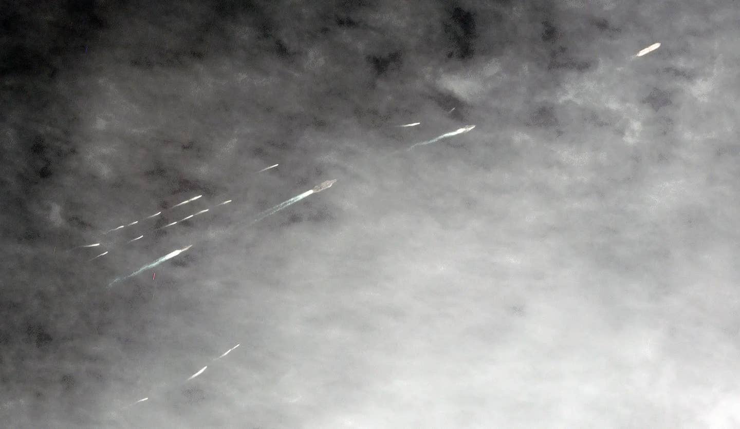 A filtered and enhanced version of the Planet Labs satellite image showing the aircraft carrier USS <em>Abraham Lincoln</em> and other ships in its strike group, as well as a commercial tanker at top right, sailing through the Strait of Hormuz while being closely shadowed by a large group of small Iranian boats in 2019. <em>PHOTO © 2019 PLANET LABS INC. ALL RIGHTS RESERVED. REPRINTED BY PERMISSION</em>