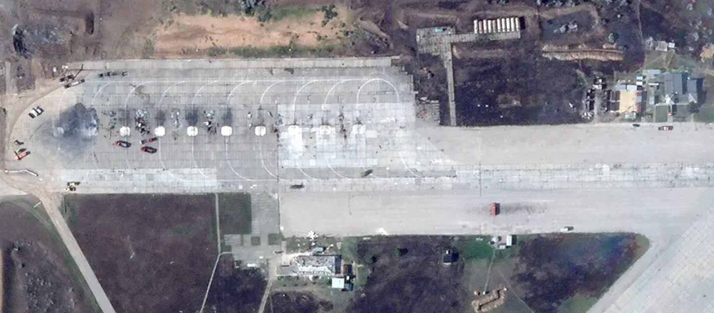 A close-up of the ramp at the southwestern end of Saky airbase on August 10, 2022, showing the remains of multiple aircraft. Fire trucks and other vehicles can be seen, as well. There is visible damage to the structures to the immediate south and east, too. <em>PHOTO © 2022 PLANET LABS INC. ALL RIGHTS RESERVED. REPRINTED BY PERMISSION</em>