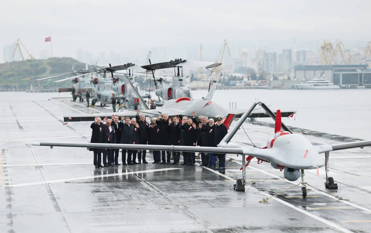 Turkish officials stand behind a Bayraktar TB3 drone on the deck of TCG <em>Anadolu</em>. <em>Photo by Murat Kula/Anadolu Agency via Getty Images</em>