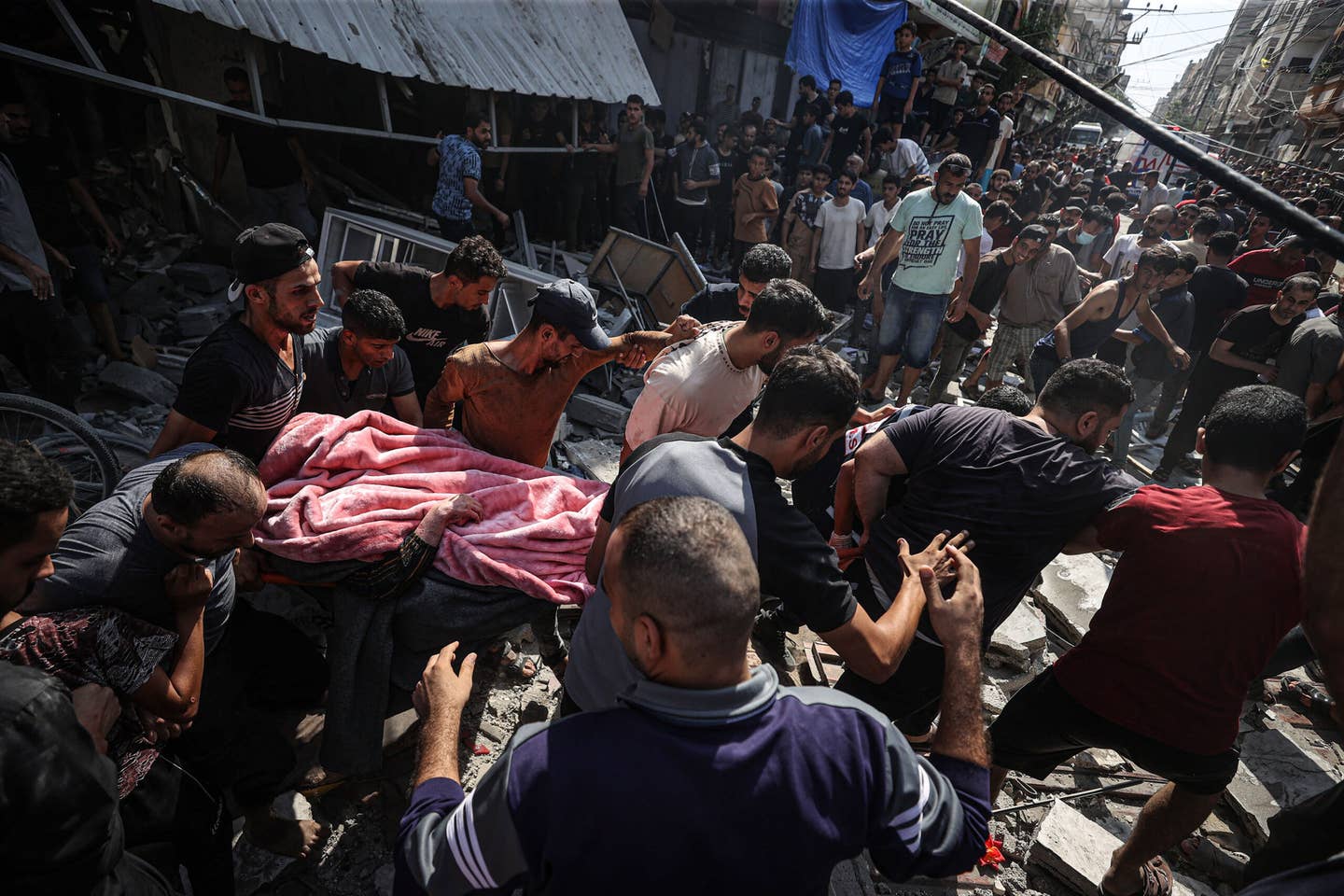 People carry a dead body of a child pulled from rubble as civil defense teams and civilians conduct search and rescue operations and debris removal work after Israeli attacks by warplanes and artillery fire in Khan Yunis, Gaza on October 24, 2023. (Photo by Mustafa Hassona/Anadolu via Getty Images)