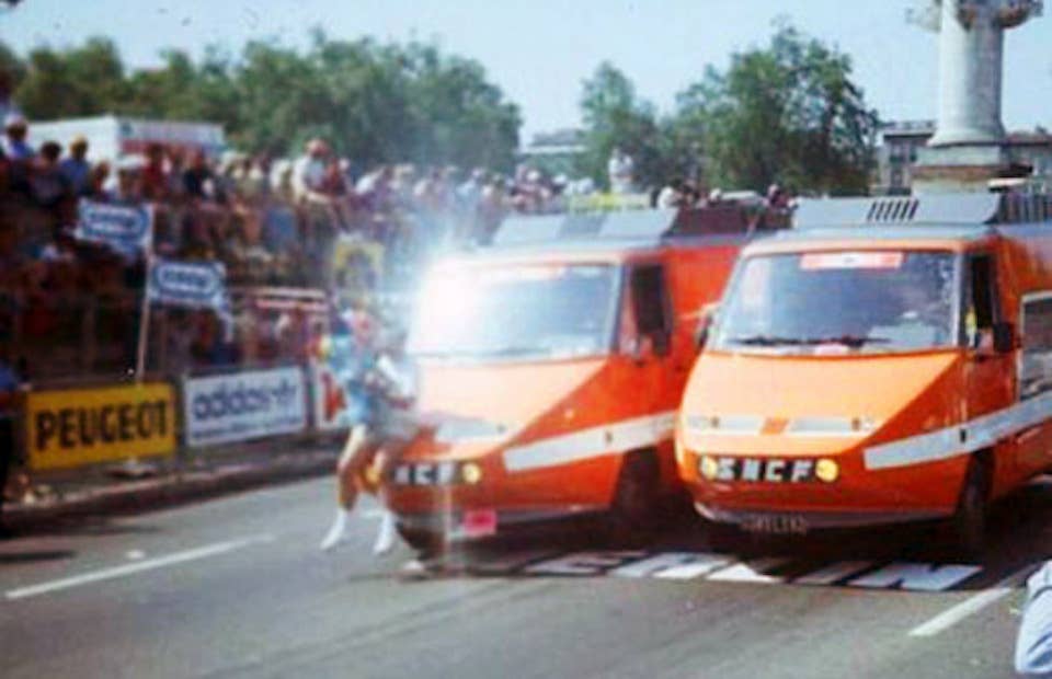 An unknown individual rides on the front of the TGV vans