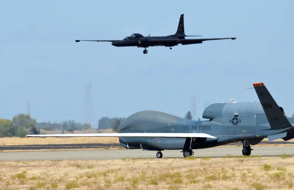 An RQ-4 Global Hawk in the foreground on a taxiway at Beale Air Force Base in California, with a two-seat TU-2S Dragon Lady trainer seen coming in to land in the background. <em>U.S. Air Force</em>