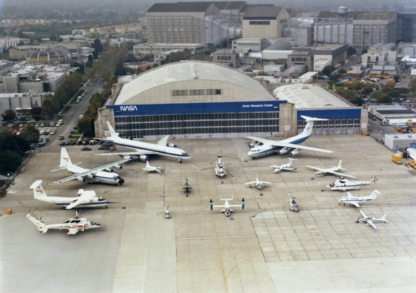 A stunning photo of the varied Ames test aircraft on the ramp in 1986. Visible are the DC-8, C-130, QSRA, Sikorsky Rotor Systems Research Aircraft (RSRA), C-141, U-2, SH-3G, King Air, YO-3A, T-38, CH-47, Learjet, AH-1G, AV-8B, OH-58A, XV-15, and UH-1H. <em>Ron Allen</em>