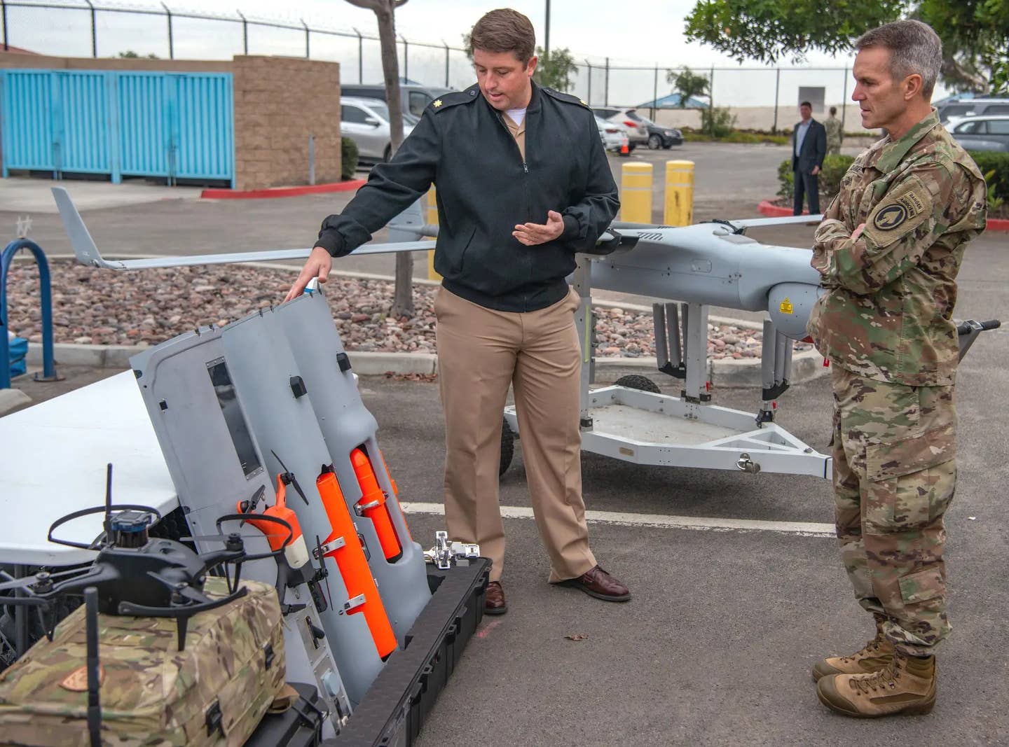 An individual assigned to Naval Special Warfare Command, at left, shows payload modules for the RQ-21 Blackjack, including one holding a small quadcopter-type drone, to U.S. Army Gen. Richard Clarke, commander of U.S. Special Operations Command, December 13, 2021. <em>U.S. Navy</em>