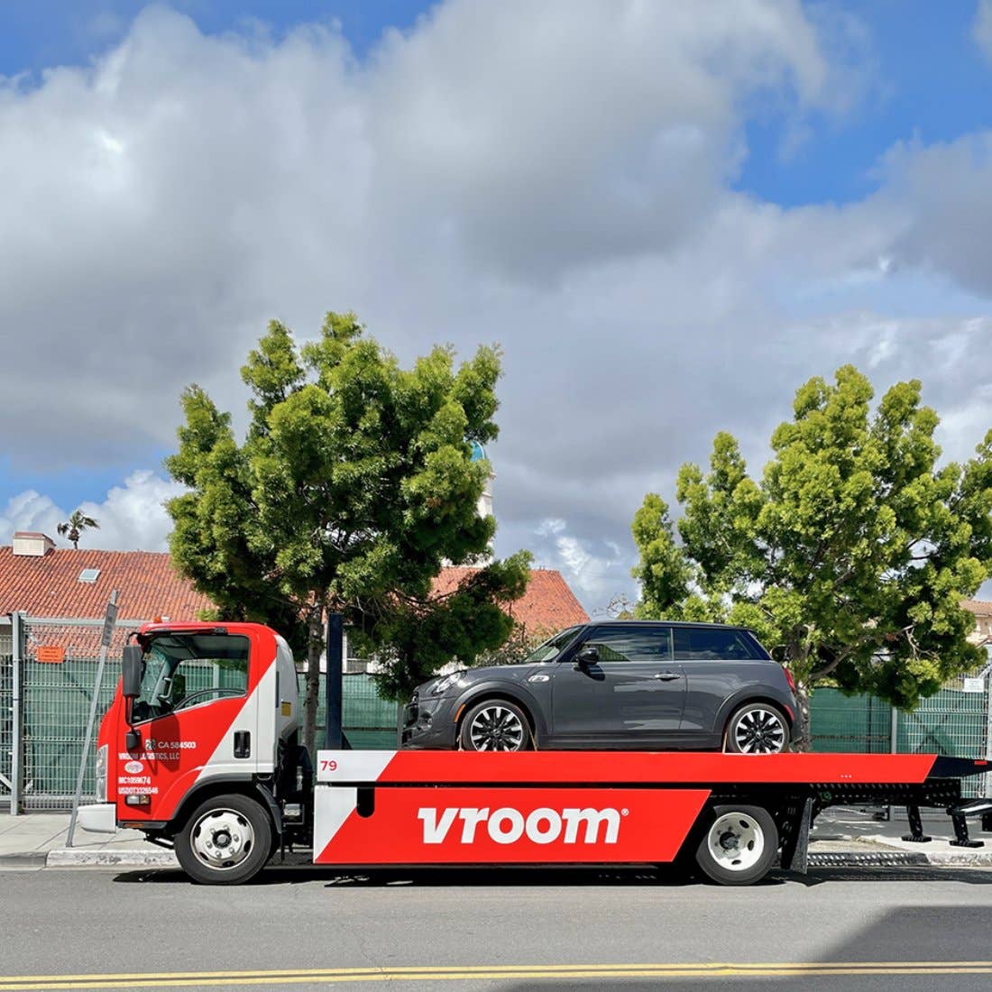 A Mini hatchback on the back of a Vroom flatbed truck.