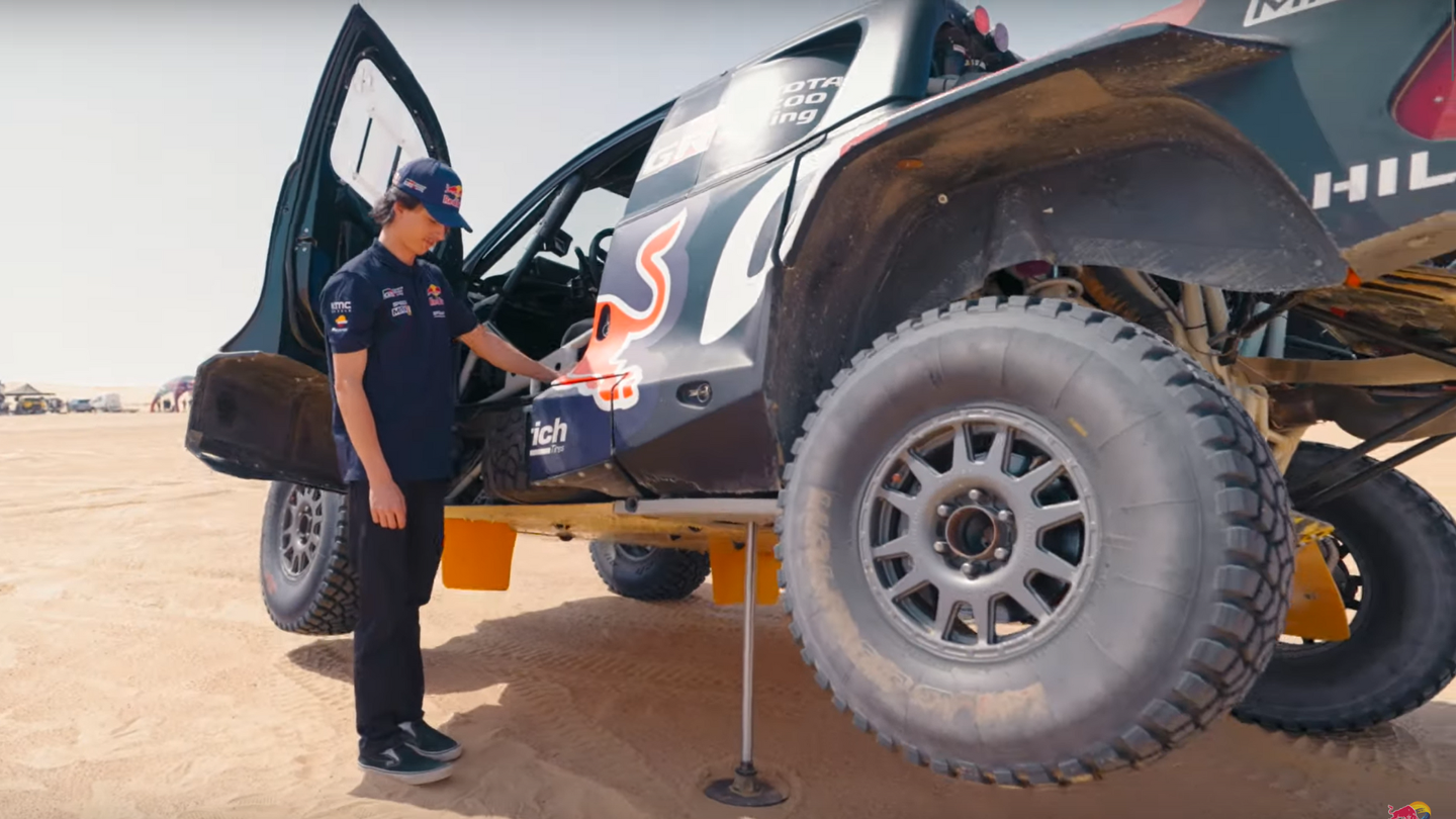 man standing next to a jacked-up race truck